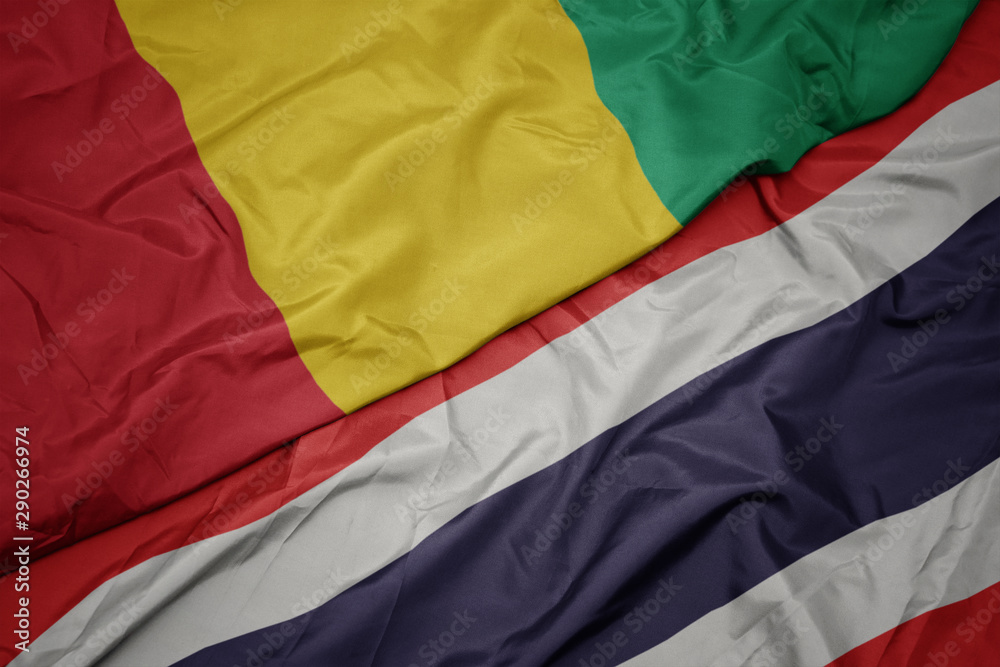 waving colorful flag of thailand and national flag of guinea. waving colorful flag of thailand and national flag of guinea.