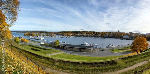Panorama of the city and boat parking from the hill. A pier for small ships on the lake on a sunny autumn day. In front of the pier are old fortifications and earthen shaft.