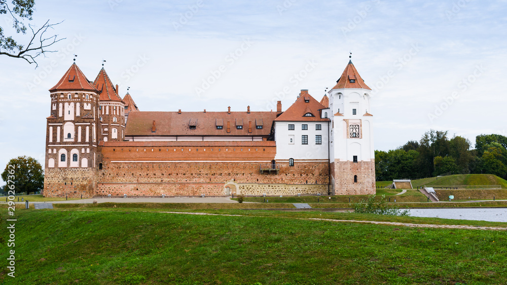 Panorama of the castle in the city of Mir in Belarus. Castle against a cloudy sky with a bridge over a water channel.