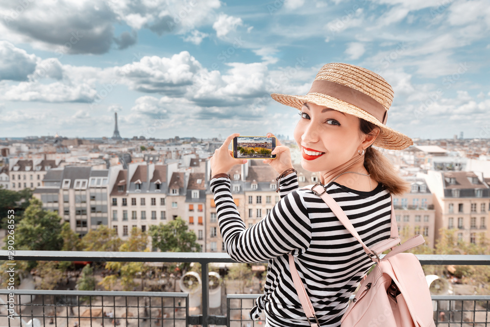 Asian girl travel blogger taking photo of Parisian cityscape by cell phone. Tourist destinations and mobile photography concept