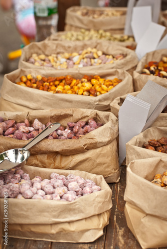 Many different nuts are sold at the fair. Nuts are sorted into paper bags.