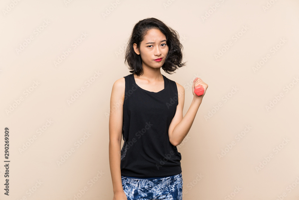 Young Asian girl making weightlifting over isolated background with sad expression Young Asian girl making weightlifting over isolated background with sad expression
