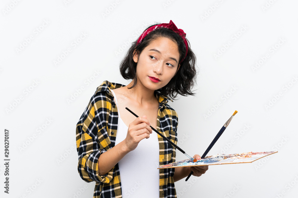 Young artist woman holding a palette over isolated white background Young artist woman holding a palette over isolated white background