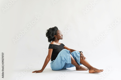Fototapeta Naklejka Na Ścianę i Meble -  african woman dressed in casuals sitting on white