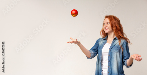 Beautiful redhead girl throwing apple in the air photo