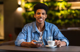 Cheerful black teen guy drinking coffee at cafeteria