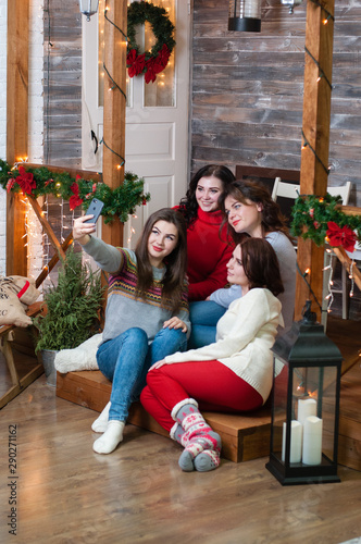 Сompany of beautiful women taking selfie on a smartphone in the Christmas interior of the house © queen1987