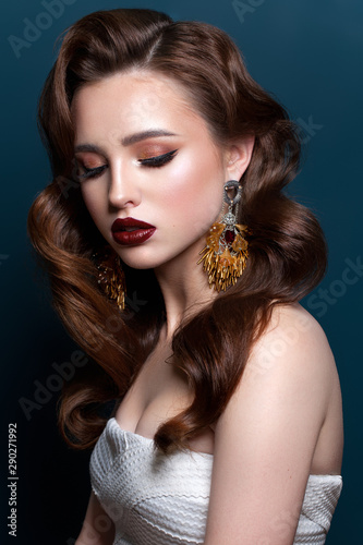 Young beautiful girl with the fashion make-up, red lips, long designer earrings, wave hairstyle