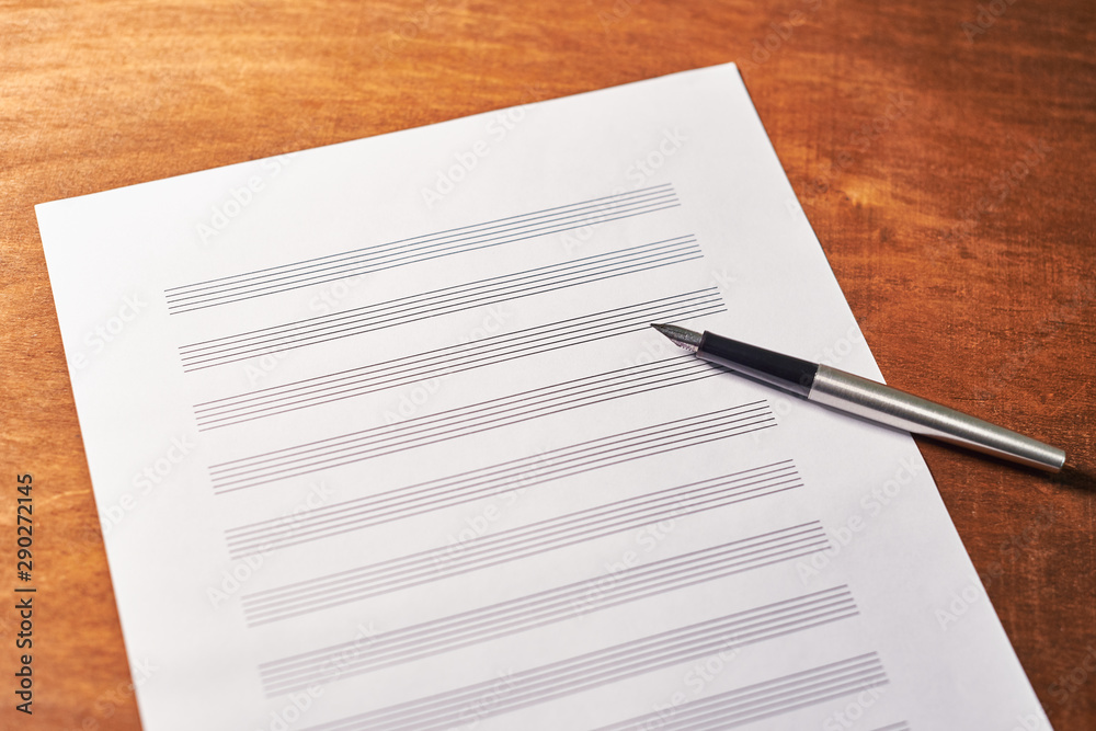 on a wooden table a white sheet of musical notes for recording. inspiration concept. on a wooden table a white sheet of musical notes for recording. inspiration concept.