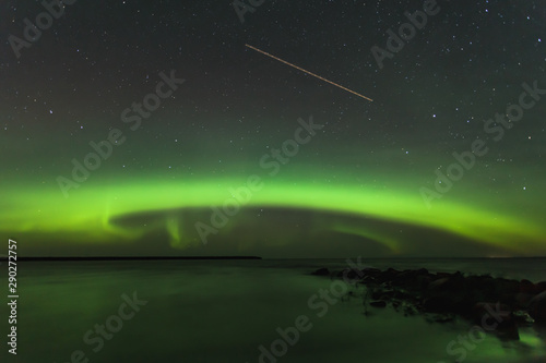 The Aurora Borealis (KP Index of 6) seen over a lake in Manitoba, Canada. A light streak of a plane passing by can be seen in the sky