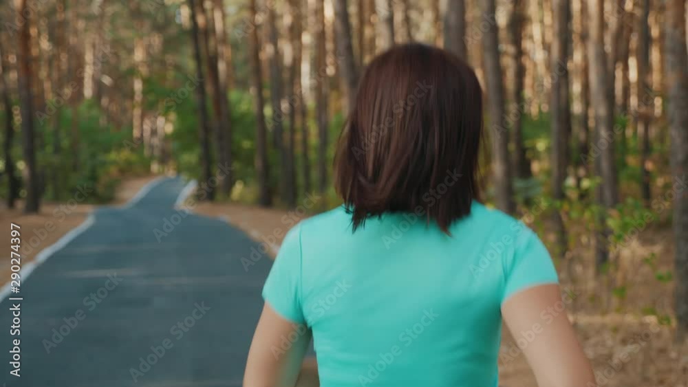Back view close-up: Athletic girl runs along the road in a pine forest, slow-motion 4k video. Female jogging outdoors Back view close-up: Athletic girl runs along the road in a pine forest, slow-motion 4k video. Female jogging outdoors