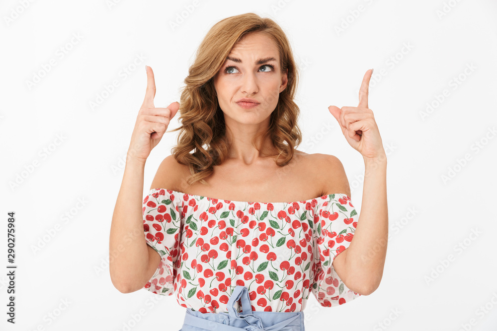 Portrait of seductive confused woman wearing summer clothes looking and pointing fingers upward at copyspace Portrait of seductive confused woman wearing summer clothes looking and pointing fingers upward at copyspace