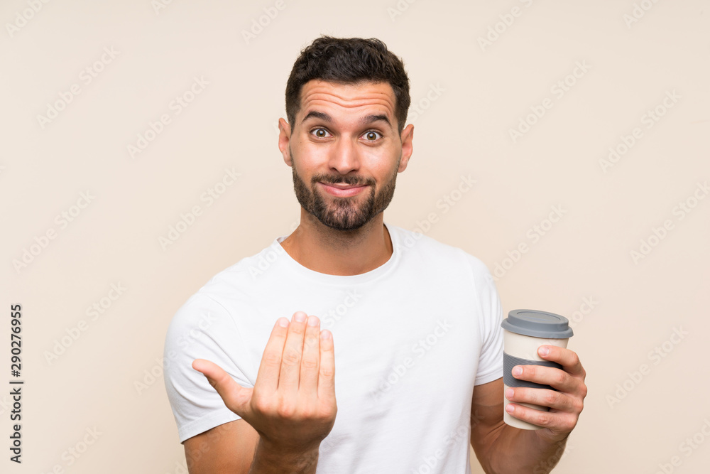 Young man with beard holding a take away coffee over isolated blue background inviting to come with hand. Happy that you came Young man with beard holding a take away coffee over isolated blue background inviting to come with hand. Happy that you came