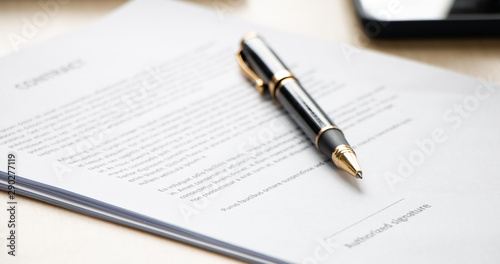 Close up of ball pen lying on a contract paper or application form on office desk, low angle view and selected focus. Signing the business contract concept.