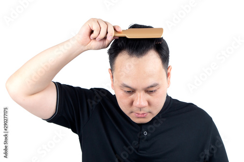 Asian bald man alopecia hand holding comb on bald head isolated on white background. Human hair loss solution and hair transplant concept.