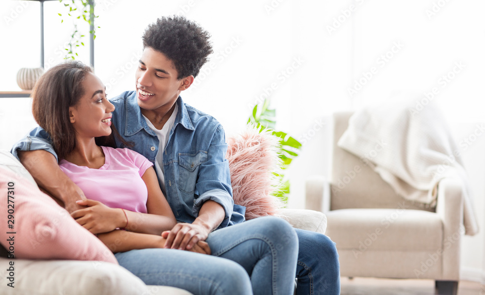 Romantic couple sitting on couch at home, embracing each other Romantic couple sitting on couch at home, embracing each other