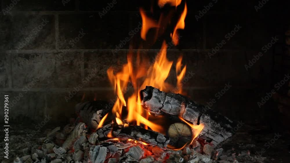 Wooden logs burning in a brick fireplace in the dark Wooden logs burning in a brick fireplace in the dark