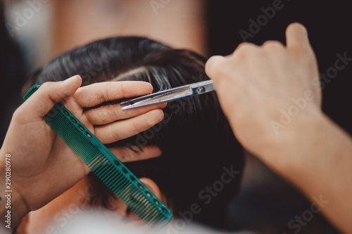 Barbershop concept. Man barber in men hairdresser does hair with scissors