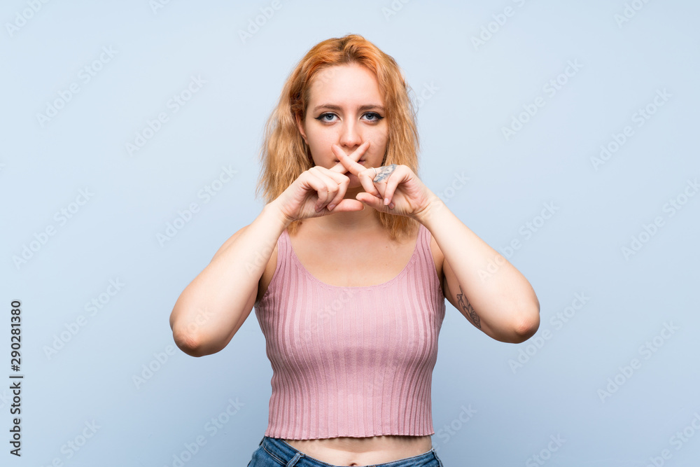 Young woman over isolated blue background showing a sign of silence gesture Young woman over isolated blue background showing a sign of silence gesture
