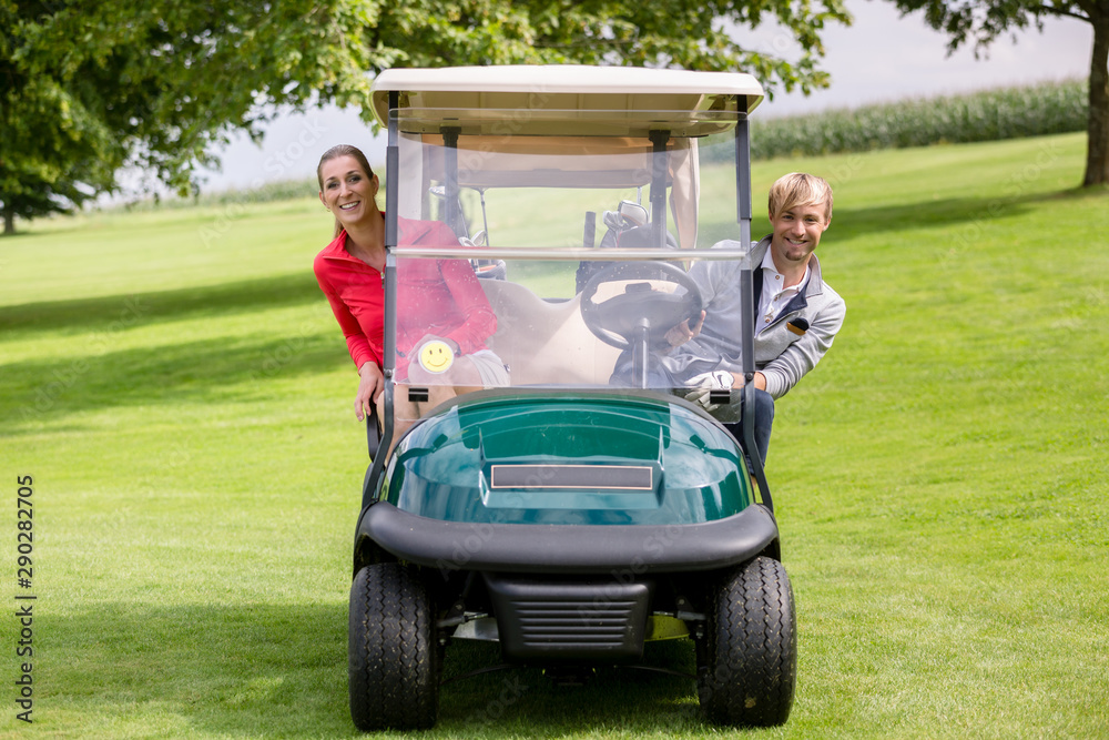 Happy couple sitting in the golf cart peeking Happy couple sitting in the golf cart peeking