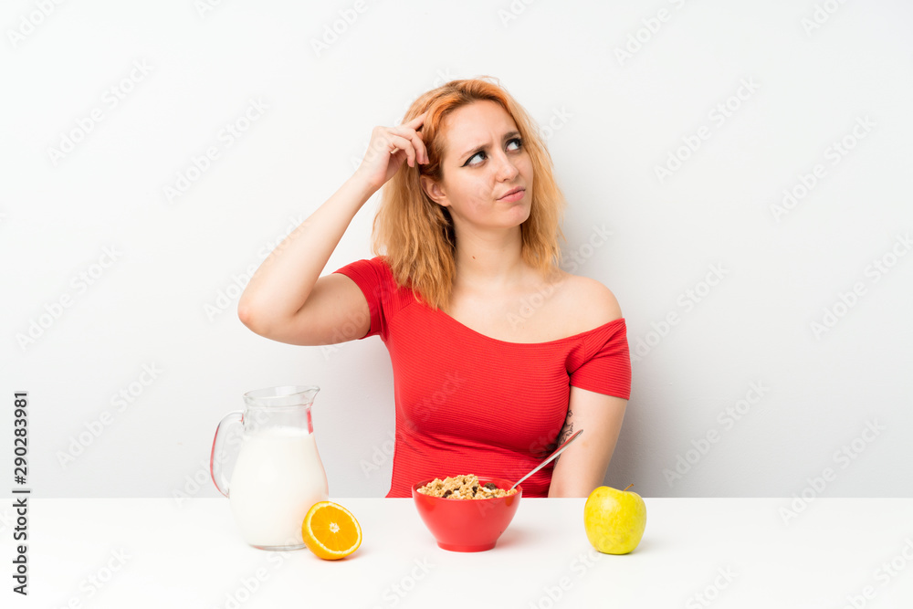 Young woman having breakfast having doubts and with confuse face expression Young woman having breakfast having doubts and with confuse face expression