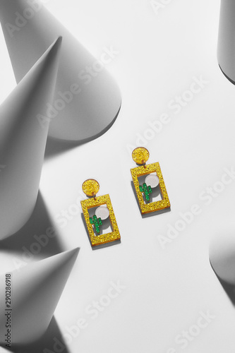 Close-up shot of a pair of sparkling stud earrings made in the form hanging picture of a cactus under the sun.  photo