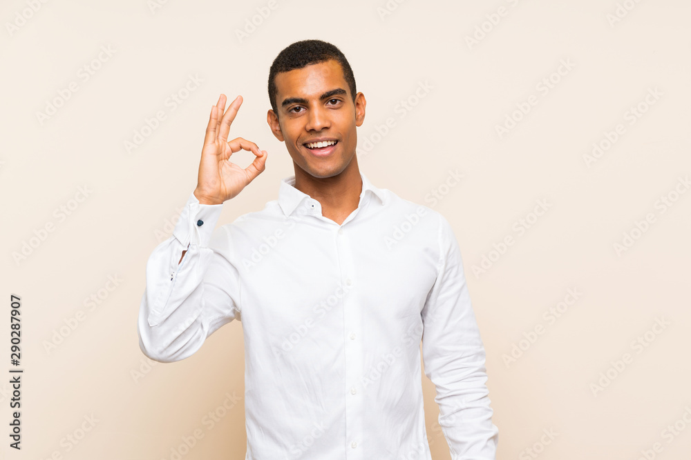 Young handsome brunette man over isolated background surprised and showing ok sign Young handsome brunette man over isolated background surprised and showing ok sign