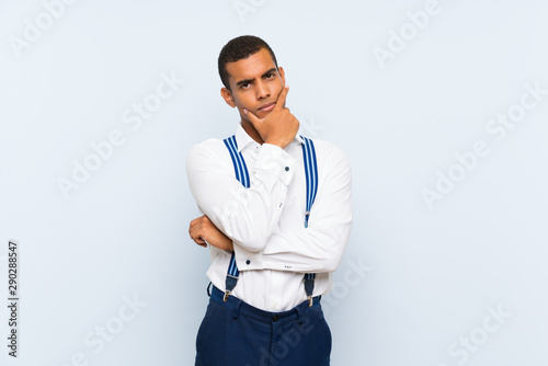 Young handsome brunette man with suspenders over isolated background thinking an idea © luismolinero