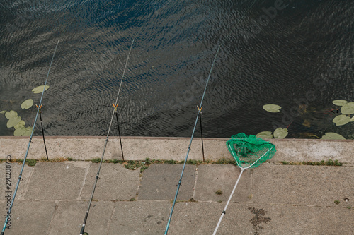 Three fishing rods are set on river bank photo