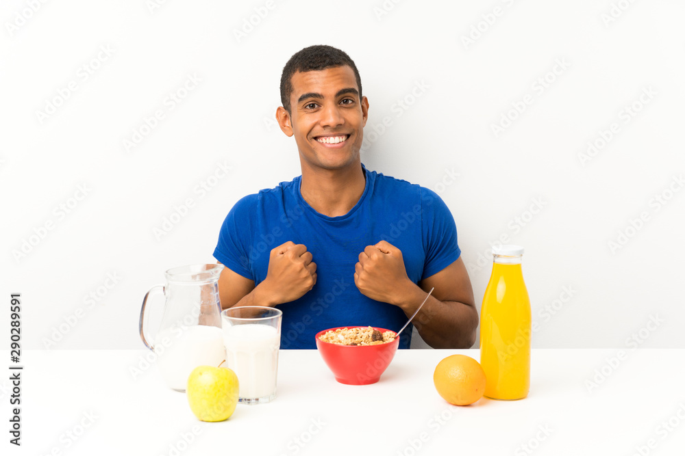 Young man having breakfast in a table celebrating a victory Young man having breakfast in a table celebrating a victory