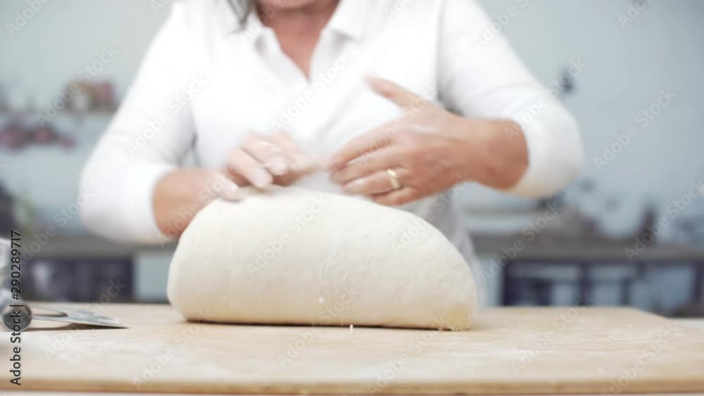 Kneading a dough to make bread, a cake, fresh pasta or pizza. Closeup of woman cook kneading to a smooth dough in a modern kitchen of a house or a bakery. Preparing organic bread on a wooden table. Kneading a dough to make bread, a cake, fresh pasta or pizza. Closeup of woman cook kneading to a smooth dough in a modern kitchen of a house or a bakery. Preparing organic bread on a wooden table.
