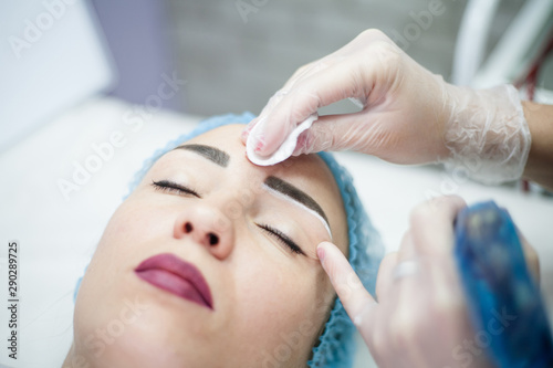 Decorative cosmetology. Eyebrow design. Closeup portrait of female client enjoying beauty procedure.