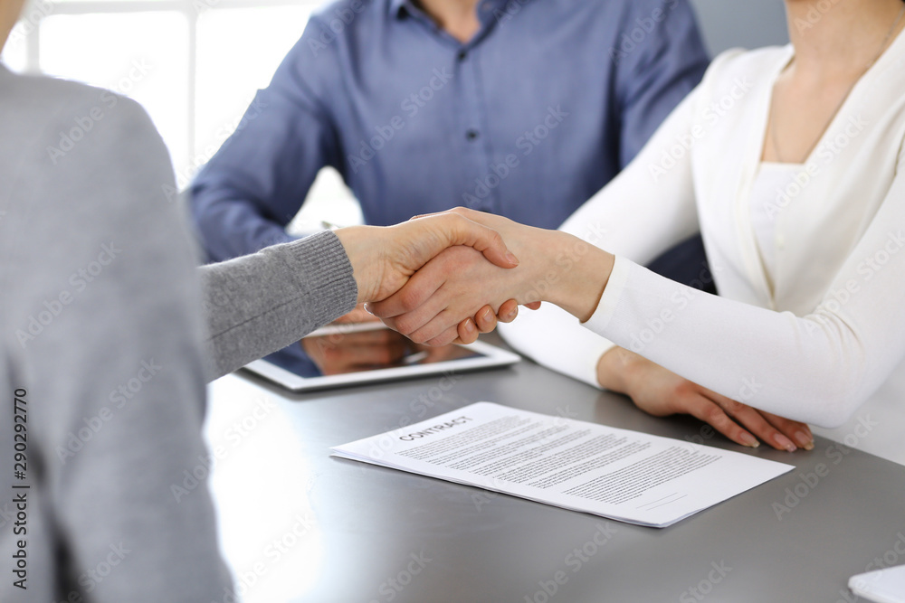 Group of business people shaking hands after discussing questions at meeting in modern office. Handshake close-up. Teamwork, partnership and agreement in business concept Group of business people shaking hands after discussing questions at meeting in modern office. Handshake close-up. Teamwork, partnership and agreement in business concept