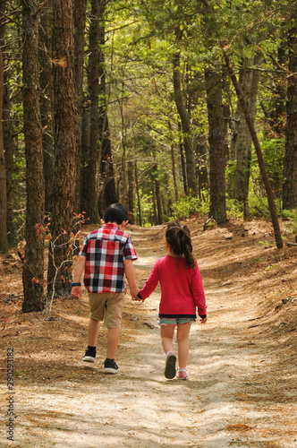 brother and sister walking hand in hand on a trail