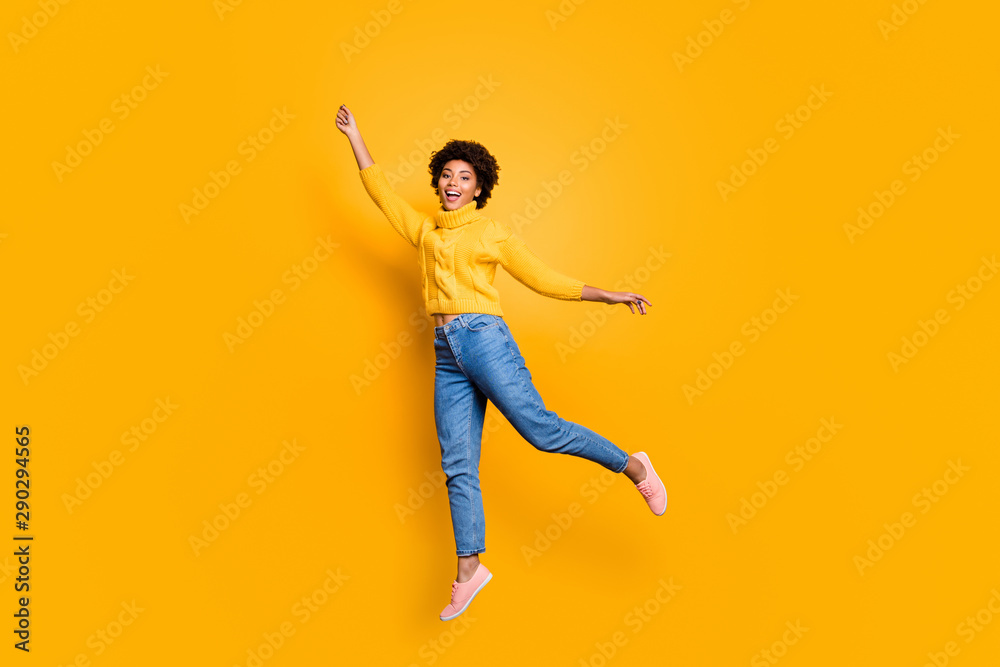 Full length body size photo of curly charming pretty sweet girlfriend feeling free wearing jeans denim yellow sweater footwear jumping up flying away isolated vivid color background
