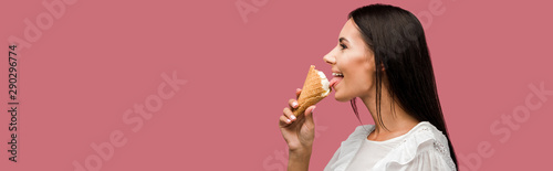 panoramic shot of happy woman eating tasty ice cream isolated on pink