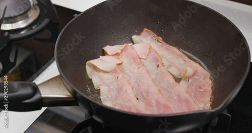 Cooking bacon on the fry pan in kitchen for breakfast
