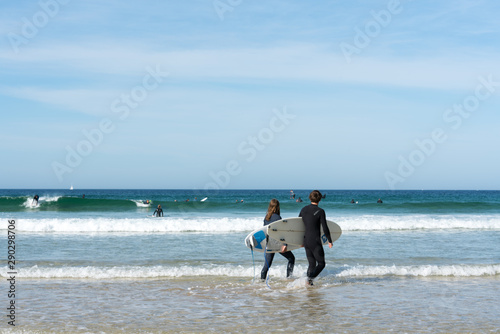 young surfers walking into the ocean and surfing on the west coast of Brittany in France at Toulinguet Beach near Camaret-Sur-Mer