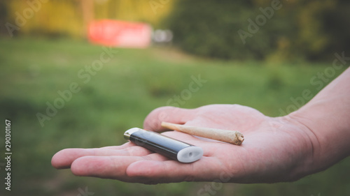 Close-up of males hands holding marijuana joint, smoking cannabis blunt outdoors.