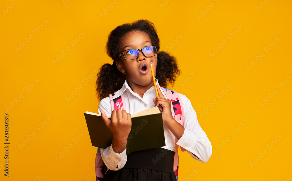 Amazed Afro Schoolgirl Doing Homework Holding Book And Pencil, Studio Amazed Afro Schoolgirl Doing Homework Holding Book And Pencil, Studio