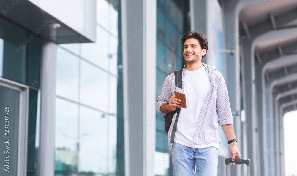 Cheerful guy going to flight registration, enjoying future travel Cheerful guy going to flight registration, enjoying future travel