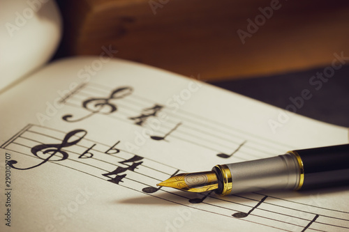 Wallpaper Mural Music notes and old book on wooden table background in morning light. Writing chords by vintage pen. Closeup and copy space for text. Concept of Music lovers. Torontodigital.ca