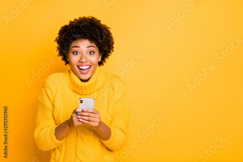 Copyspace photo of cheerful nice cute charming curly girlfriend black skinned wearing yellow pullover with collar holding phone in her hands while isolated with bright color background