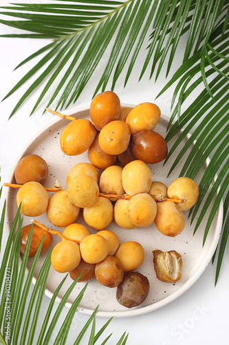 Fresh raw yellow dates with palm leaf