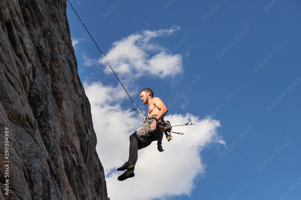 Fototapeta premium El joven Jorge desciende rapelando, después de haber escalado por una pared vertical en la Pedriza, en la Sierra de Madrid