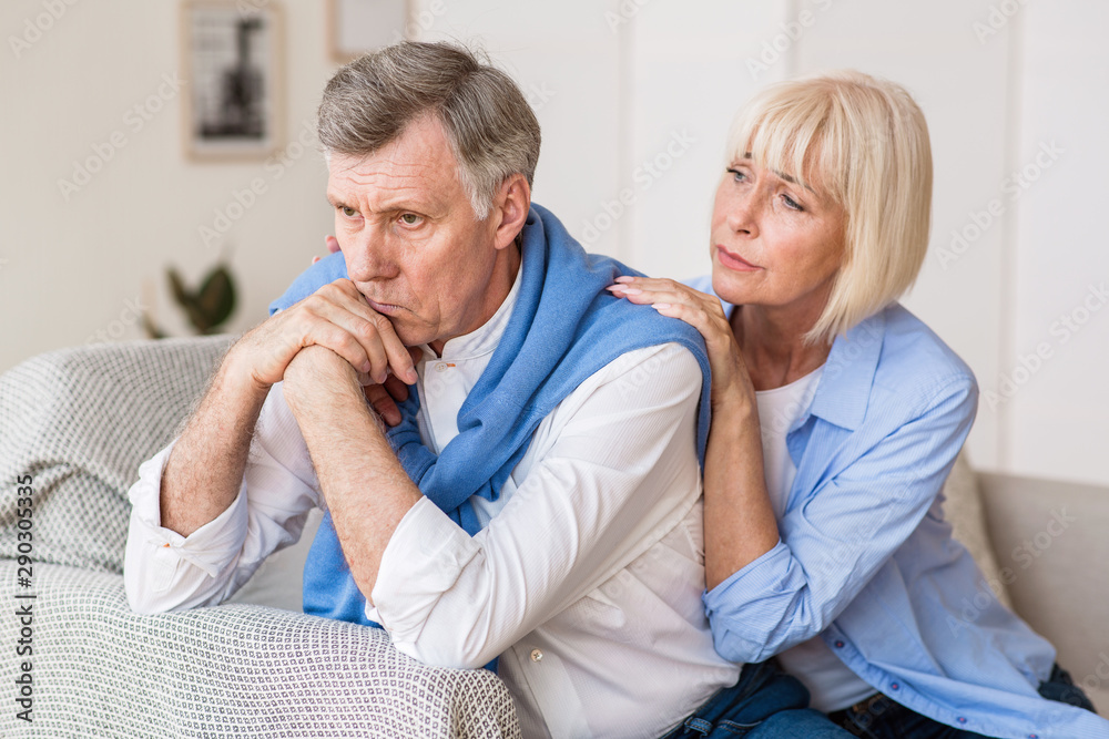 Senior woman consoling husband after arguing at home Senior woman consoling husband after arguing at home