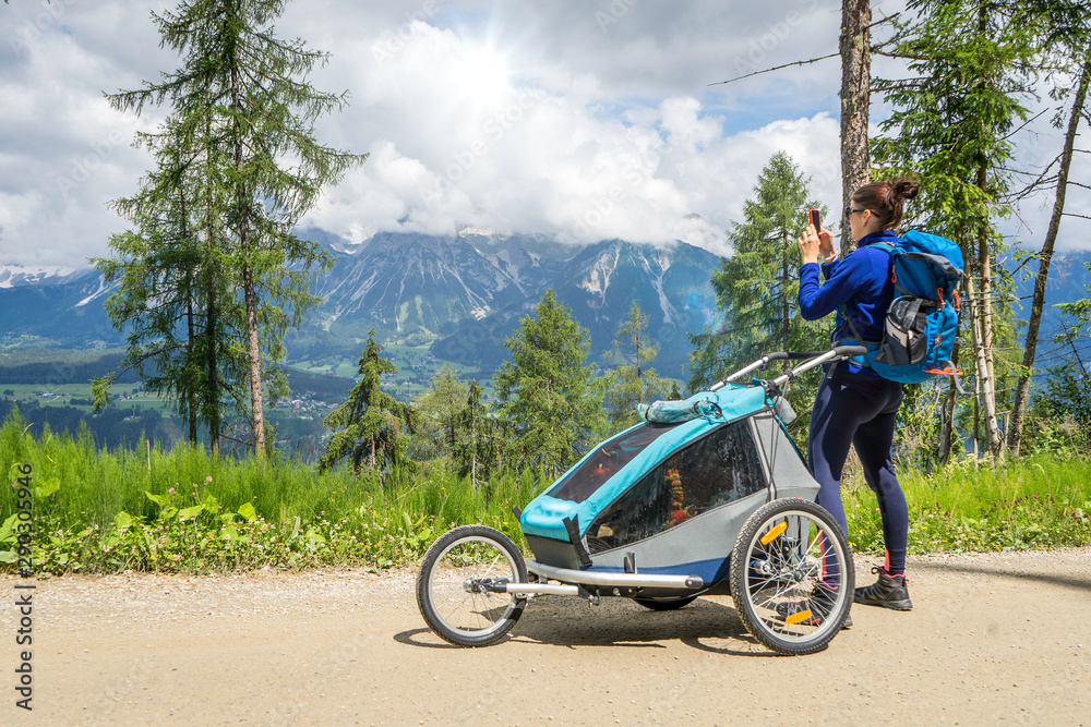 Young Beautiful women mom hiking with baby in jogging stroller i
