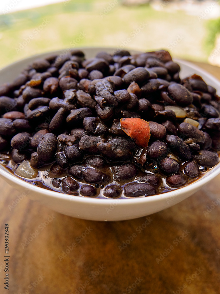 black beans in soup, served in a deep plate on a wooden table black beans in soup, served in a deep plate on a wooden table