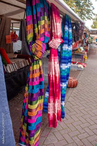 Colourful fabrics hanging from a market stall © Roel