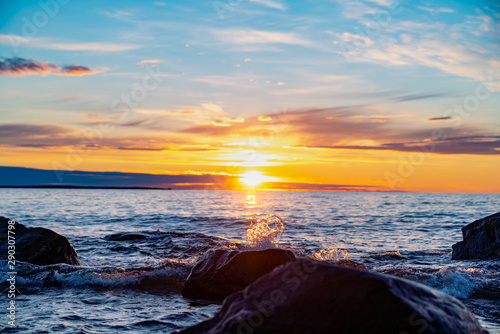 Waves splashing over the rocks in the summery sun set in Hållnäs, Sweden